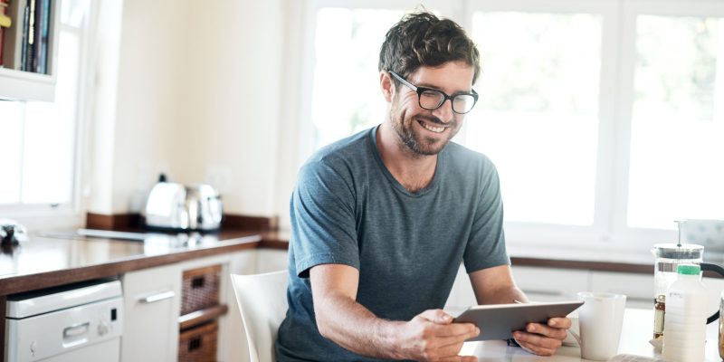 It's not the morning without a digital news feed Shot of a young man using a digital tablet while having breakfast in the kitchen at home