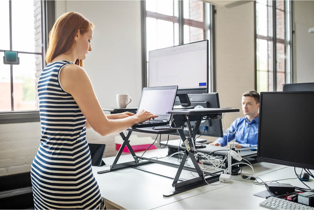 Photo of a woman in an office setting using a stand-up desk